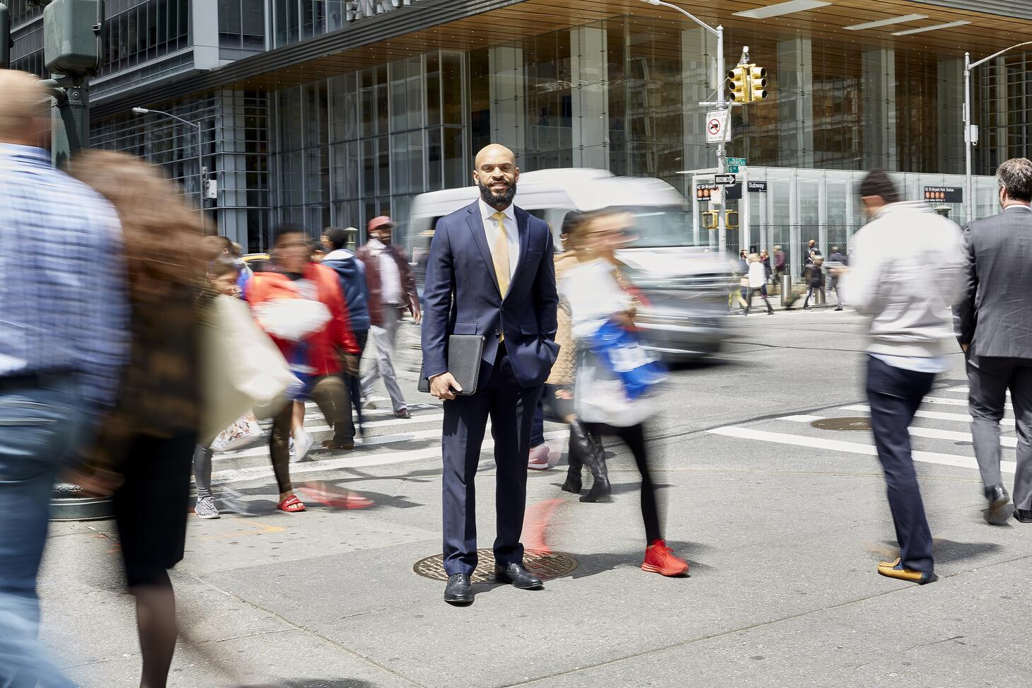 An EMBA student stands on a busy street corner before a meeting in midtown