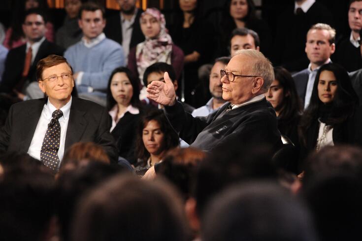 Warren Buffet speaks with Bill Gates during a university event