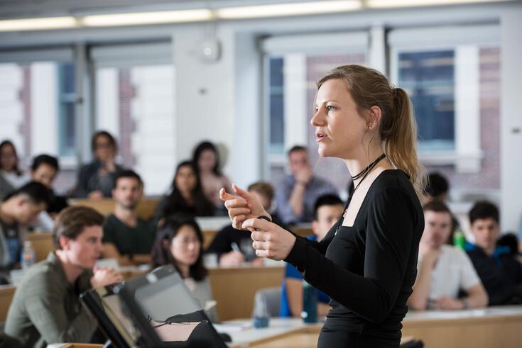 A professor delivers a lecture to a crowded classroom